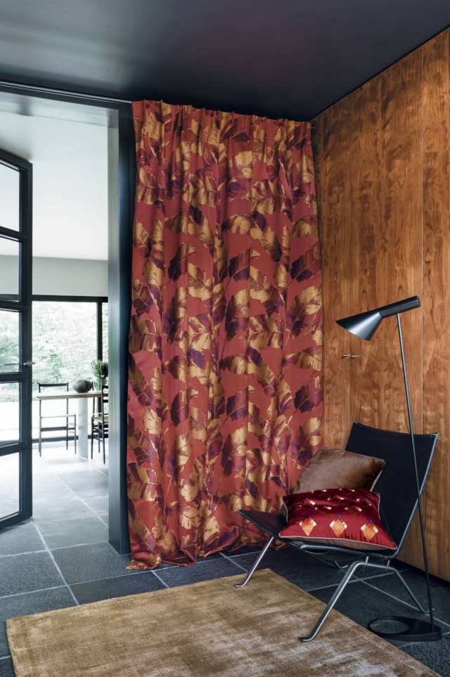 Cortines Frunzides Casamance Cortines frunzides en tons marrons amb cadira i catifa davant de fons imatges de finestres