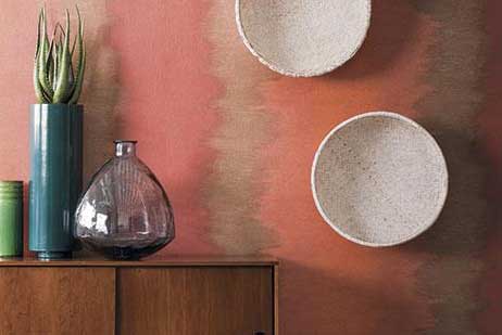 Pared roja con dos cuencos y un jarrón de adorno sobre cajonera de madera