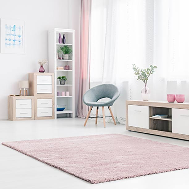 Sala de estar de decoración clásica y colores cálidos con muebles cajoneras en madera butaca y gran ventana con cortina de lino